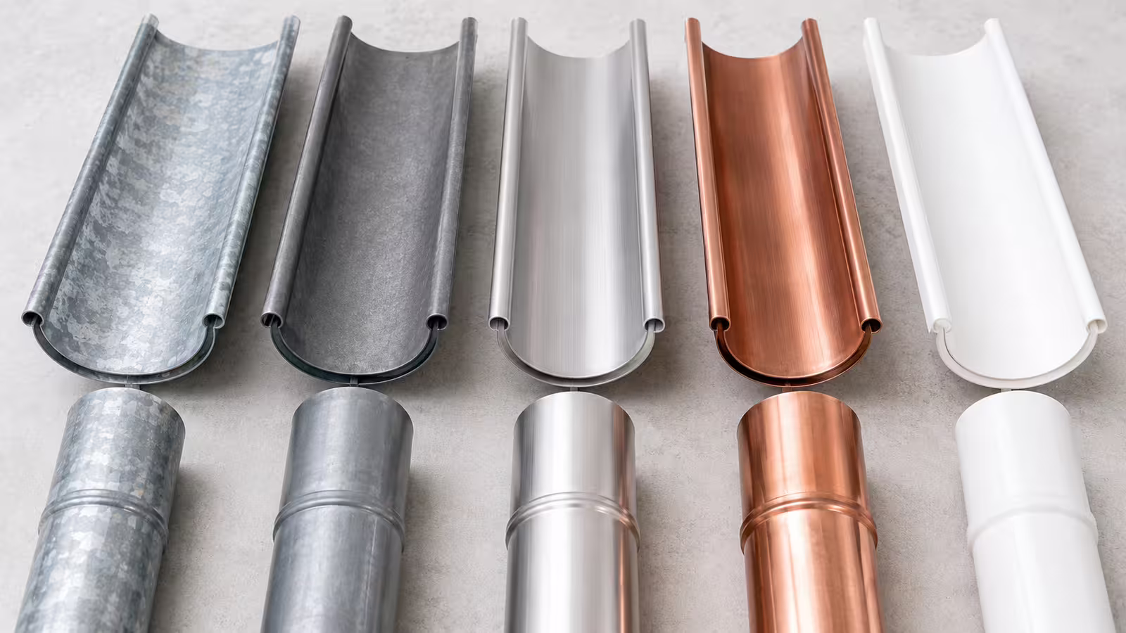 Různé materiály okapů vedle sebe: pozink, titanzinek, hliník, měď a plast